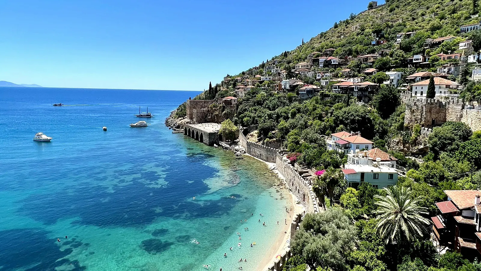 The old town of Alanya on its peninsula, the castle wall running down to a turquoise cove.